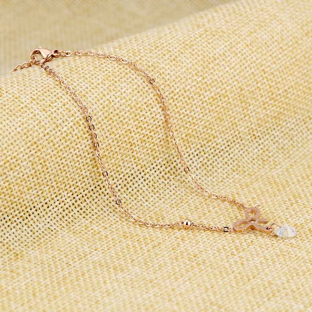 An anklet with a crystal sparkling diamond and a studded-bow over a yellow textured canvas