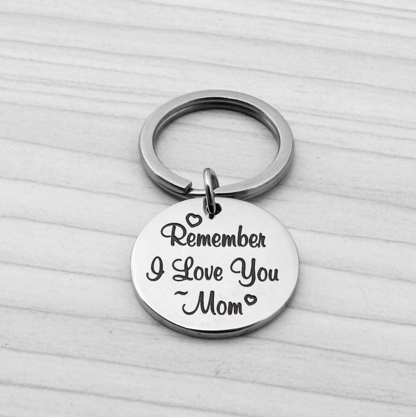 A stainless steel keychain gift for mom over a white wooden surface