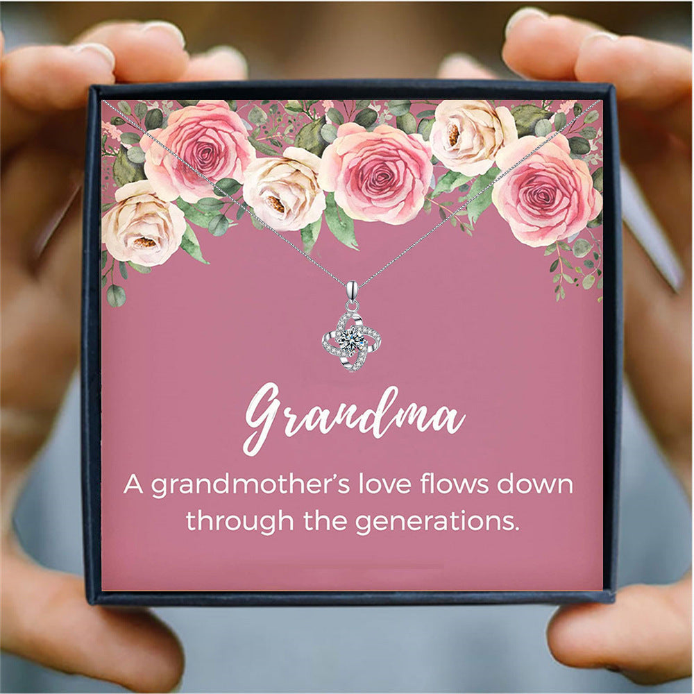 someone holding a pink card box with a silver heart necklace for grandma