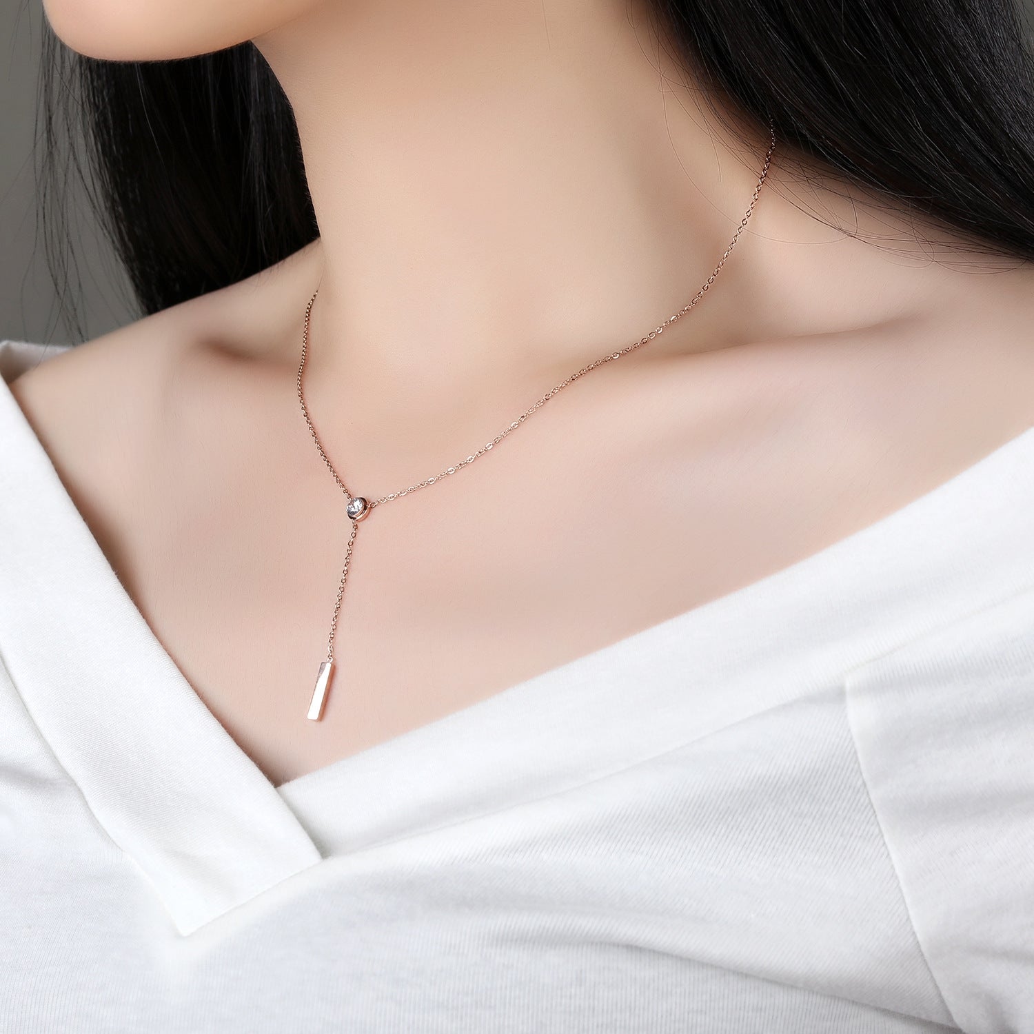 A woman wearing an elegant rose gold long necklace with a diamond