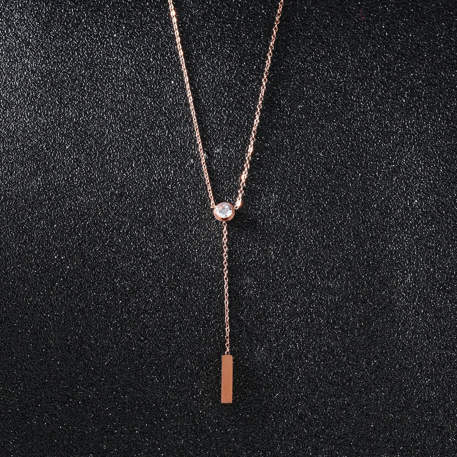 elegant rose gold necklace with a diamond on a black canvas