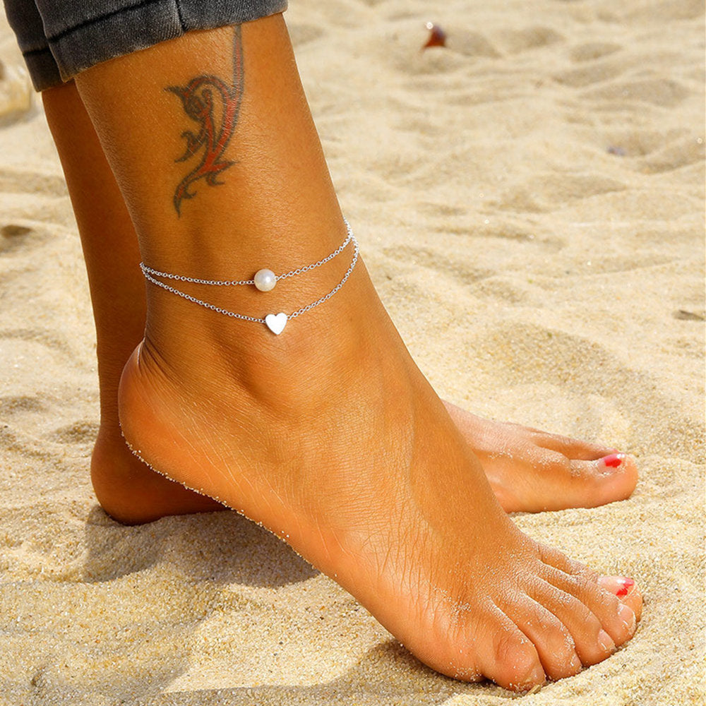 a woman's ankle wit a silver love beach anklet 