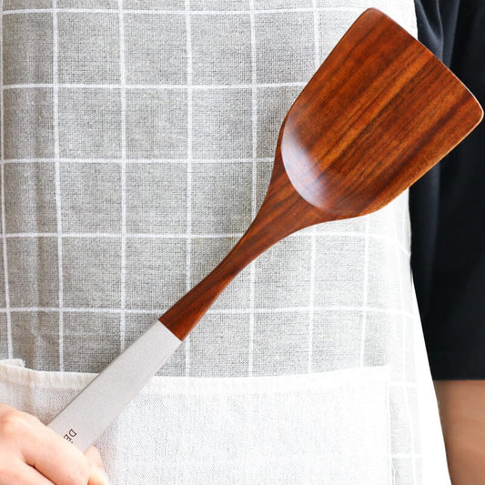 Hand holding an eco-friendly teak wood spoon