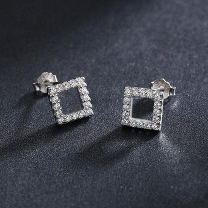 silver square earrings over a black textil surface