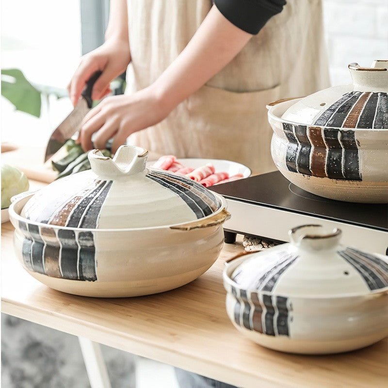 Ceramic casseroles with stripes on a a kitchen countertop and a woman cutting veggies 
