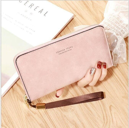 a woman's hand holding a vegan leather pink hand wallet