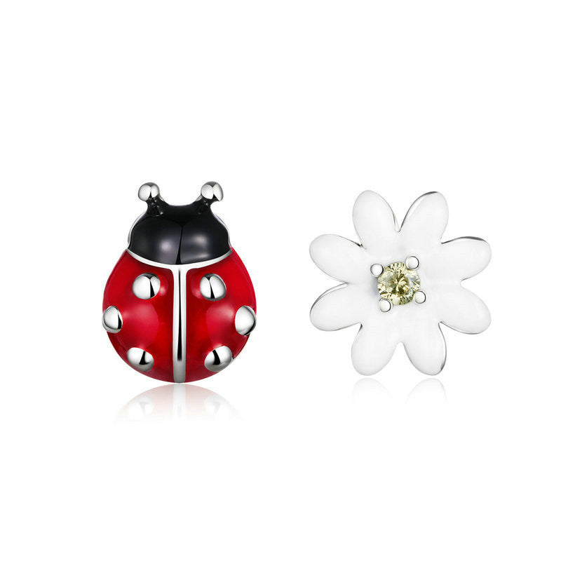 A pair of ladybug earrings on a white canvas