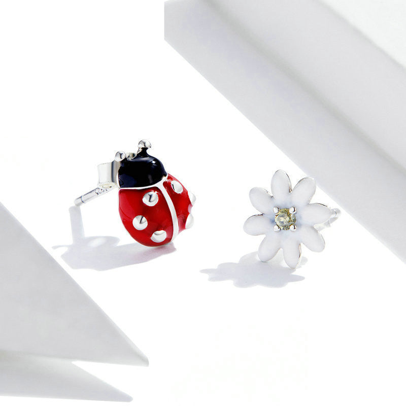 Close view of a pair of  silver ladybug theme earrings in a white canvas