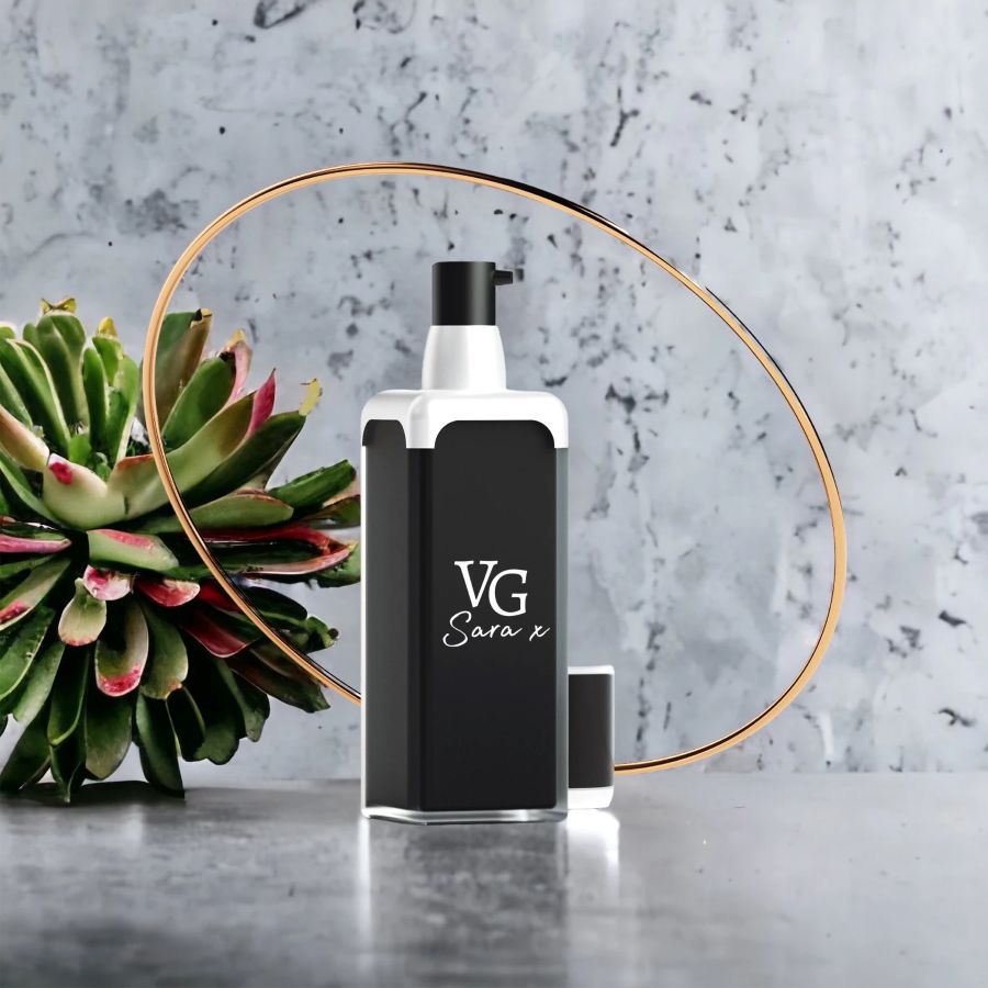 Black and white bottle of serum with a Logo brand VG Sara x on a grey marble countertop beside  cactus 