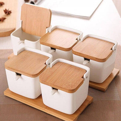 A set of four bamboo and wood clamshell ceramic seasoning jars with wooden handles presented on a table