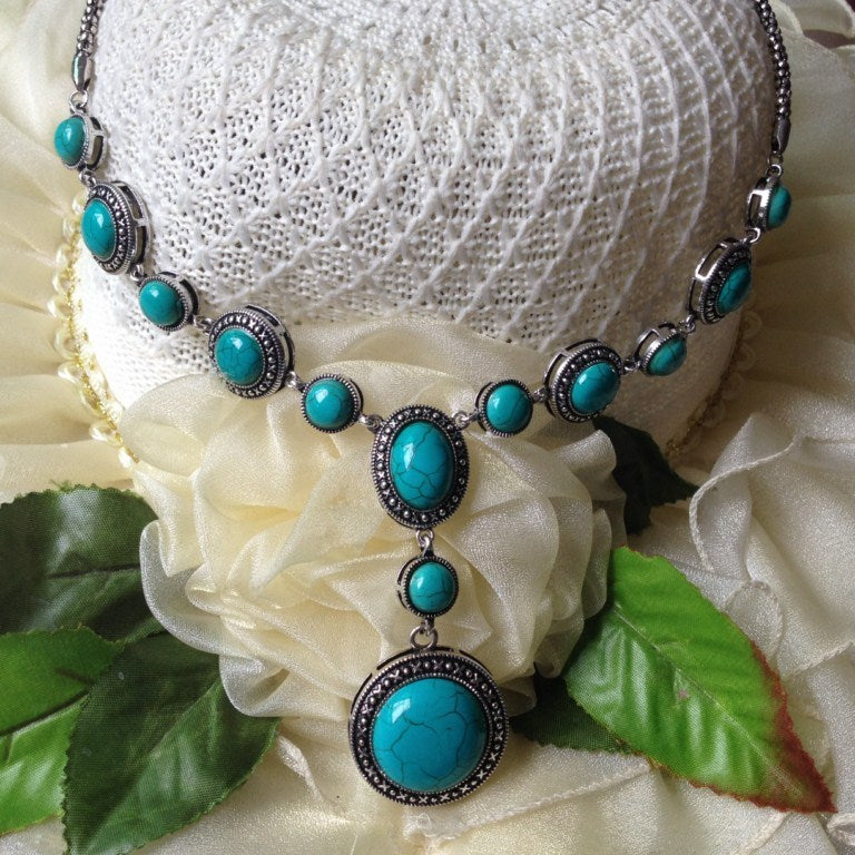 A polished alloy necklace featuring a round-shaped pendant with blue turquoise gemstones