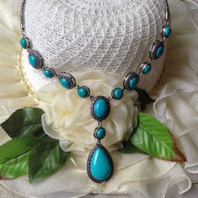 “An ecoElegant polished alloy necklace featuring a water drop-shaped pendant with blue turquoise gemstones