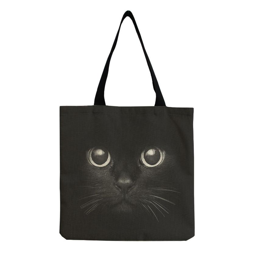 the face of a black cat printed on a black tote bag