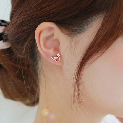 A woman wearing a a gold rose butterfly earring