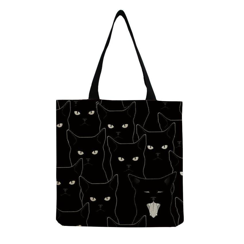 several  black cat faces printed on a  black tote bag