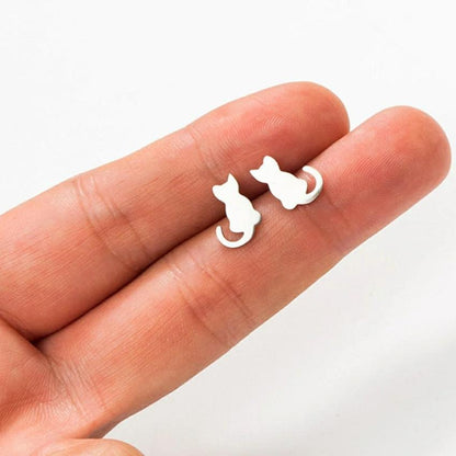 A pair of silver earrings hold by 2 human fingers