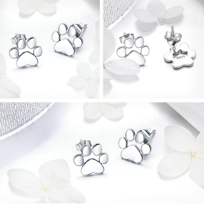 A pair of silver dog paws earrings on a white background and white flowers