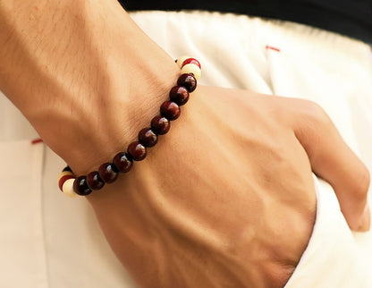 An adult's hand wearing a charming red wine wood beaded bracelet