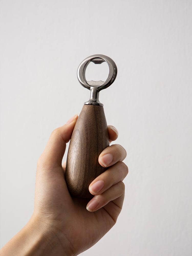 Close-up of a hand gripping a vintage stainless steel bottle opener