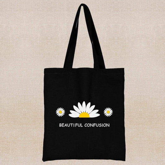 An eco-friendly and sustainable black tote bag with a flower and a positive message