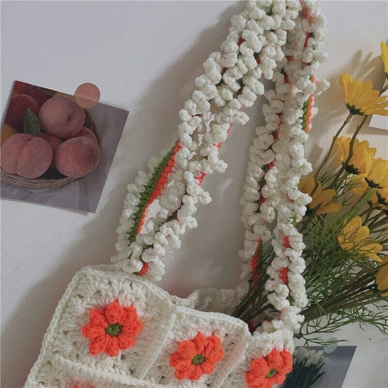 a knitted shoulder bag crochet with a orange floral pattern beside a bunch of yellow flowers