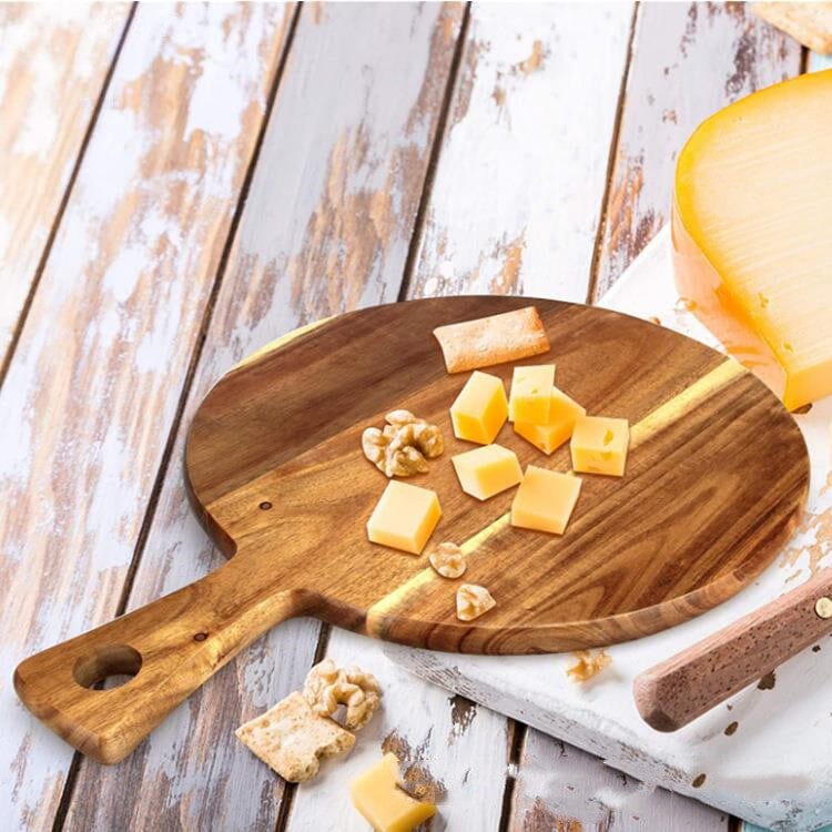 a round wood pizza board with cheese over a wooden countertop 