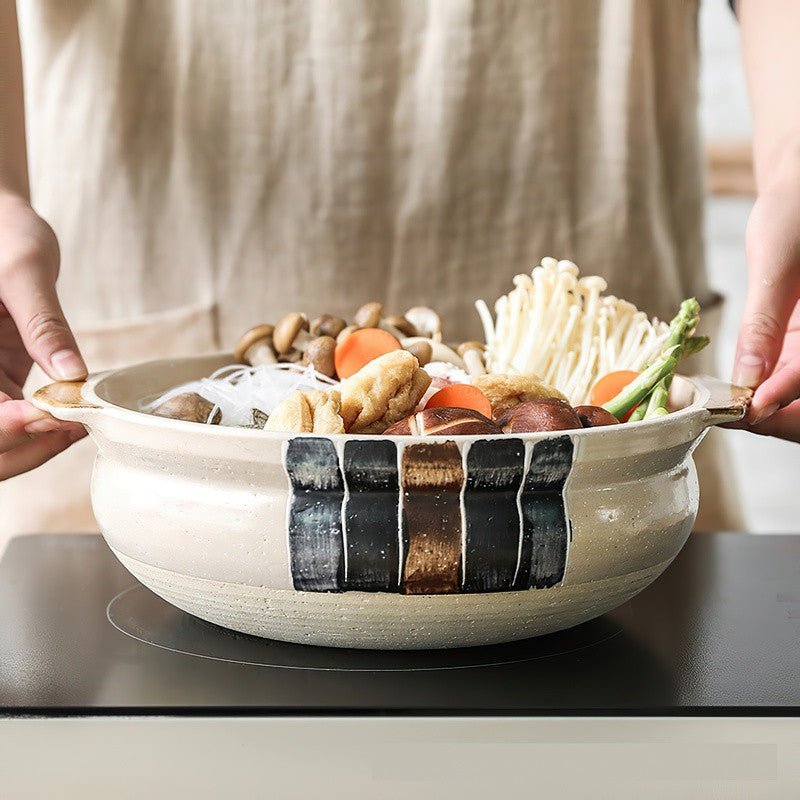 Someone cooking a stew on a ceramic casserole decorated with stripes 