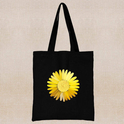 An eco-friendly and sustainable black tote bag with a yellow margarite flower in the center