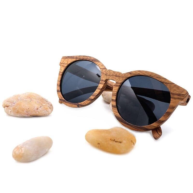 a pair of wooden sunglasses and three stones on a white canvas