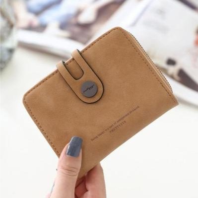 A hand holding a vegan faux leather purse for women brown color